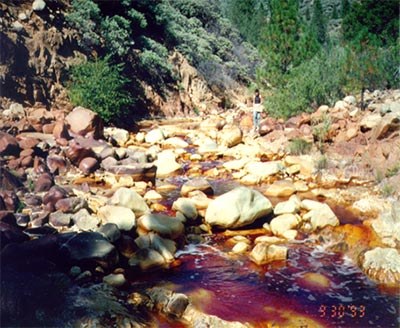 Orange-red acidic drainage flowing through a rocky stream near Iron Mountain mine